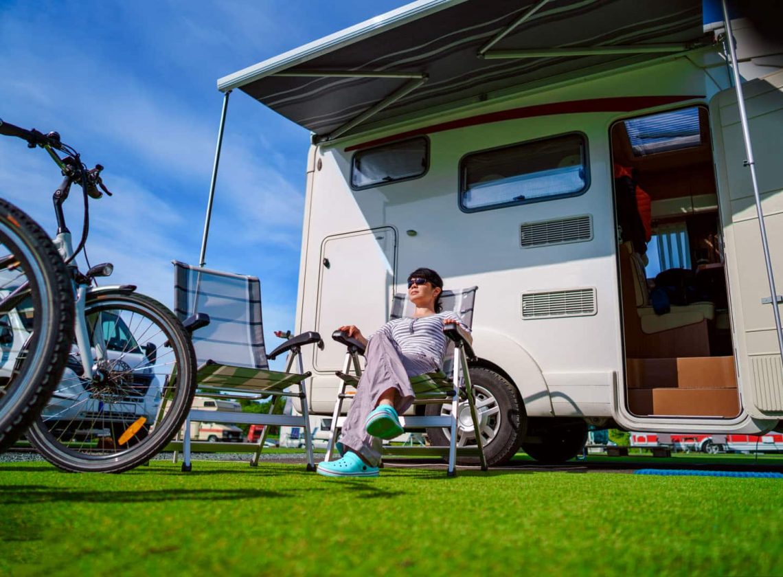 Woman resting on a chair on the nature. Caravan car Vacation. Family vacation travel, holiday trip in motorhome